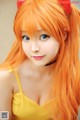 A woman with long orange hair wearing a yellow dress.