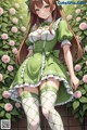 A girl in a green dress and white stockings standing in front of a wall of roses.