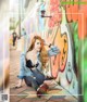 A woman sitting on the ground in front of a graffiti wall.