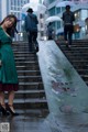 A woman in a green coat is standing on some steps.