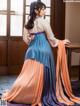 A woman in a blue and orange hanbok sitting on a table.