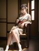 A woman in a kimono sitting on a chair.