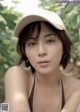 A woman wearing a baseball cap sitting on a bench.