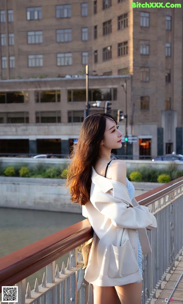 A woman standing on a bridge next to a river.