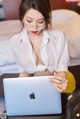 A woman sitting on a bed using a laptop computer.