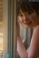 A woman looking out of a window with her hand on the window sill.