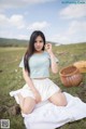 A woman sitting on a blanket in a field holding a flower.