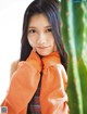 A young woman leaning against a cactus with her hand on her chin.