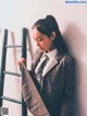 A woman in a suit leaning against a wall.