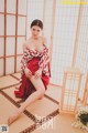 A woman in a red and white kimono sitting on a tatami mat.