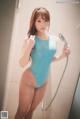 A woman in a blue bathing suit standing in a shower.