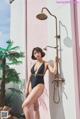 A woman in a black bathing suit standing next to a shower.