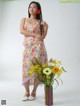 A woman standing next to a vase of flowers.