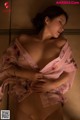 A woman in a pink robe laying on a bed.