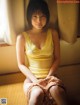 A woman in a yellow tank top sitting on the floor.