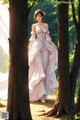 A woman in a white dress standing in the woods.