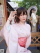 A woman in a pink kimono sitting on a bench.