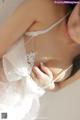 A woman in a white lingerie is posing for the camera.