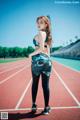 A woman in a sports bra top and leggings standing on a track.