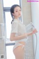 A woman in a white shirt and red panties standing in a shower.