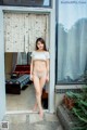 A woman in a bikini standing in front of a window.