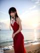 A woman in a red dress standing on a beach.