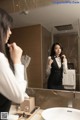 A woman standing in front of a mirror in a bathroom.