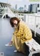 A woman sitting on a bench with a city in the background.