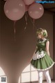 A girl in a green dress holding a bunch of pink balloons.