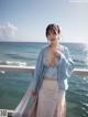 A woman in a blue kimono standing on a balcony by the ocean.