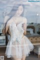 A woman in a white lingerie standing in front of a window.