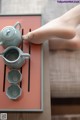 A person is putting tea in a teapot on a tray.