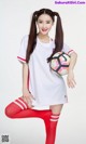 A woman in a white shirt and red socks holding a soccer ball.